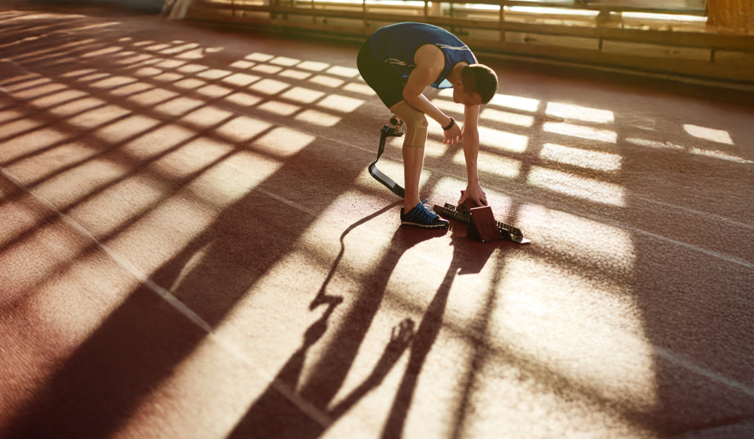 Un velocista con una protesi alla gamba sinistra sistema il blocco di partenza sulla pista di atletica