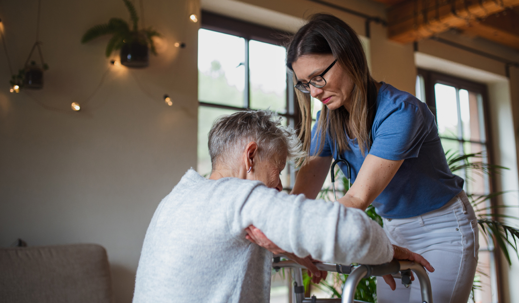 Una donna giovane aiuta un anziano a mettersi in piedi