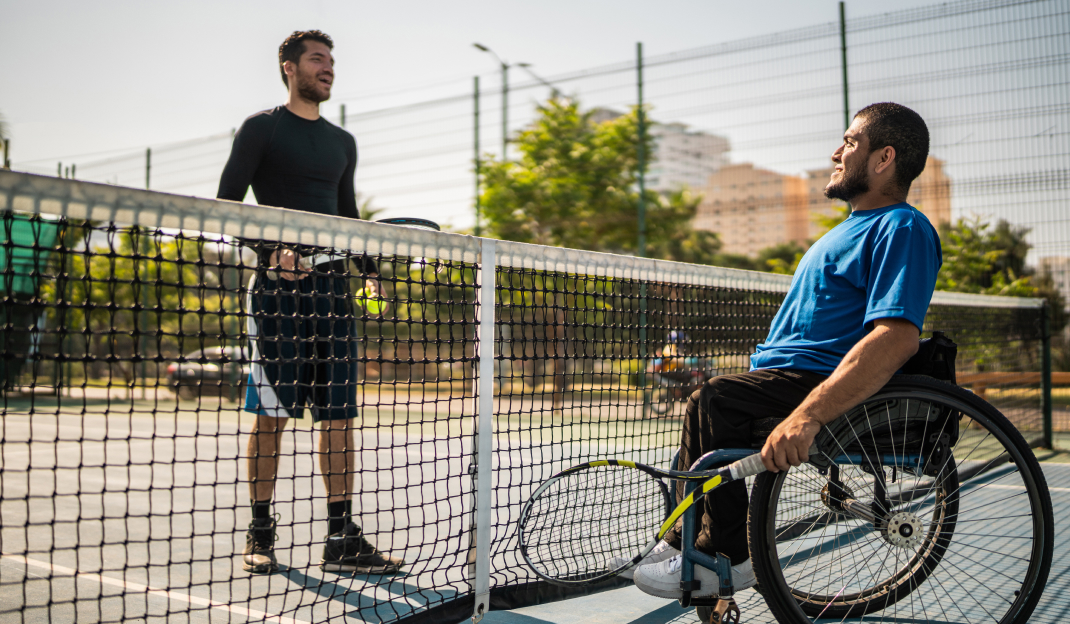 Un uomo in carrozzina gioca a tennis con il suo allenatore
